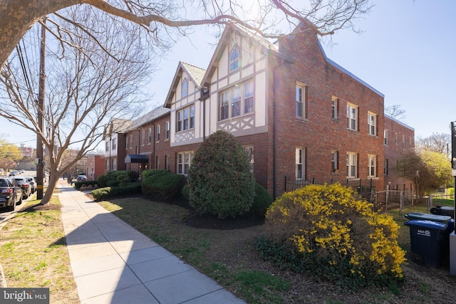view of side of home with brick siding and fence