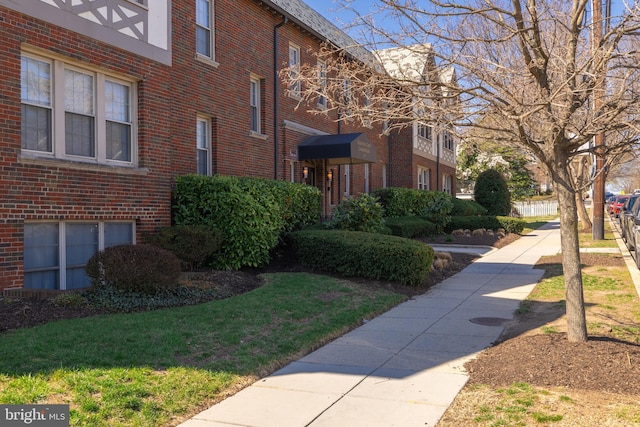 view of side of home with brick siding and a lawn