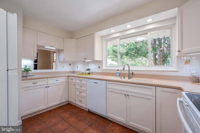 kitchen featuring white appliances, a sink, backsplash, white cabinets, and recessed lighting