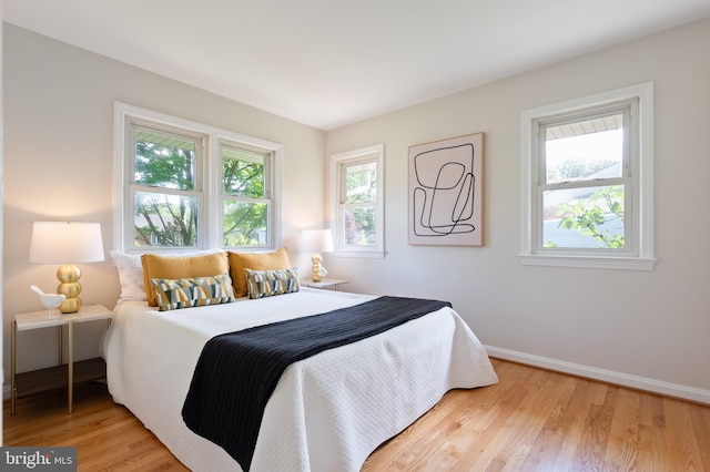 bedroom featuring light wood finished floors and baseboards