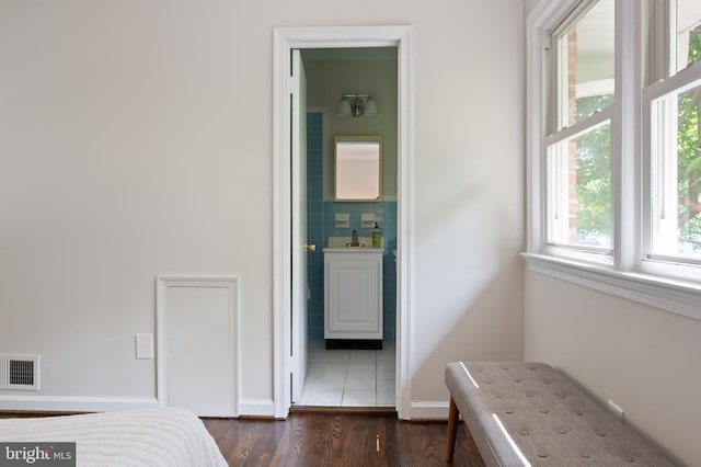 bedroom with multiple windows, dark wood finished floors, and baseboards