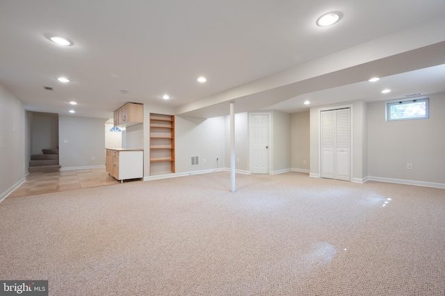 basement featuring light colored carpet, recessed lighting, baseboards, stairway, and built in shelves