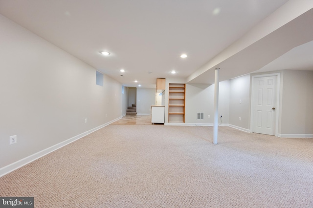 finished basement featuring baseboards, light colored carpet, recessed lighting, stairs, and built in shelves