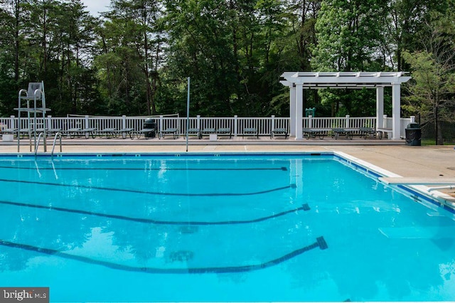 community pool featuring a pergola and view of wooded area