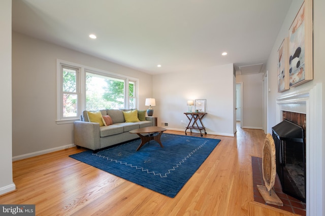 living area with a fireplace, light wood-style flooring, baseboards, and recessed lighting