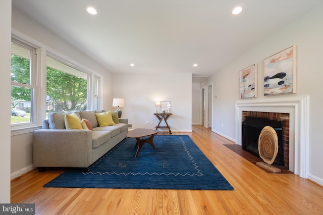living area featuring wood finished floors, recessed lighting, a brick fireplace, and baseboards