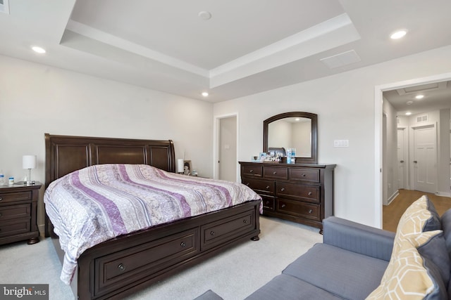 bedroom with light carpet, recessed lighting, and a tray ceiling
