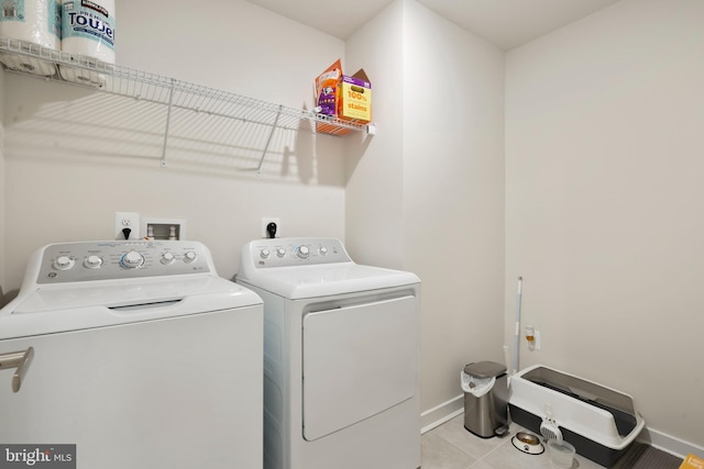 clothes washing area with separate washer and dryer, baseboards, and light tile patterned floors