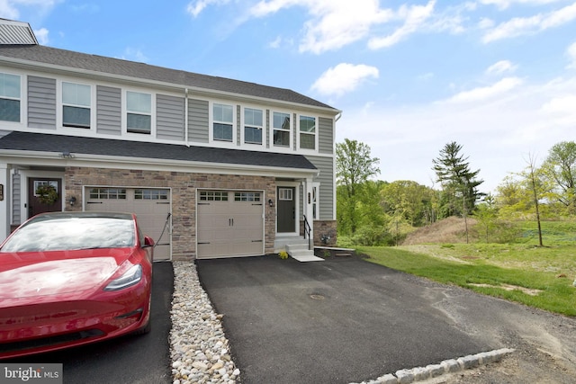 view of property with an attached garage, stone siding, driveway, and entry steps