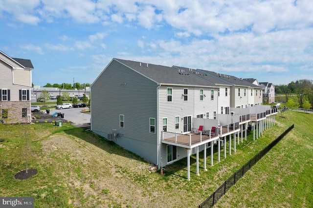 rear view of house with central AC unit and a lawn