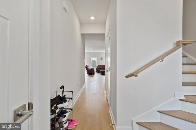 staircase featuring wood finished floors, baseboards, and recessed lighting