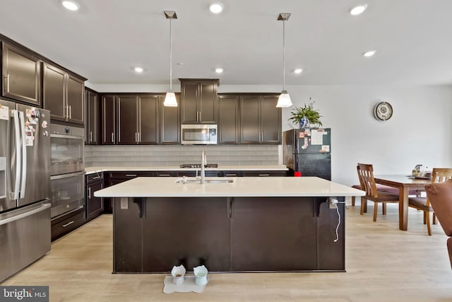 kitchen with stainless steel appliances, a sink, dark brown cabinetry, light countertops, and backsplash