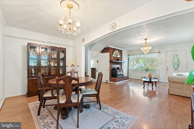 1517 Margaret St, Woodbridge, VA 22191 - dining area featuring a chandelier, a textured ceiling, a brick fireplace, light wood finished floors, and crown molding