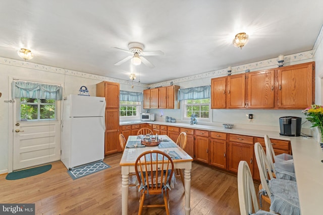 1517 Margaret St, Woodbridge, VA 22191 - kitchen with white appliances, light wood-style floors, light countertops, wallpapered walls, and brown cabinets