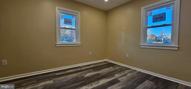 spare room featuring dark wood-style flooring, baseboards, and healthy amount of natural light