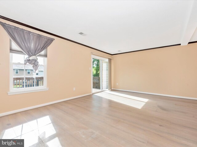 spare room with light wood finished floors, baseboards, and crown molding
