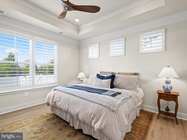 bedroom with a raised ceiling, ornamental molding, wood finished floors, baseboards, and recessed lighting