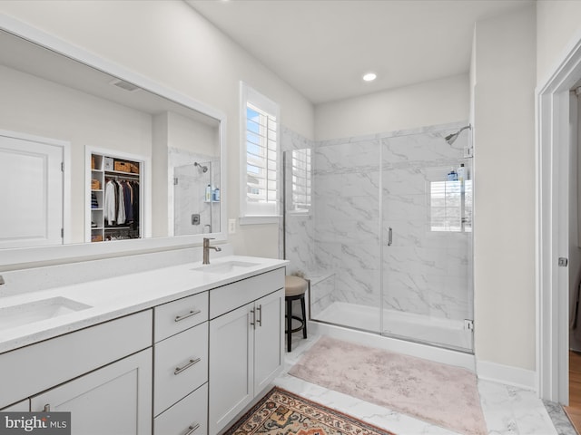 bathroom with a marble finish shower, marble look tile flooring, a walk in closet, double vanity, and recessed lighting