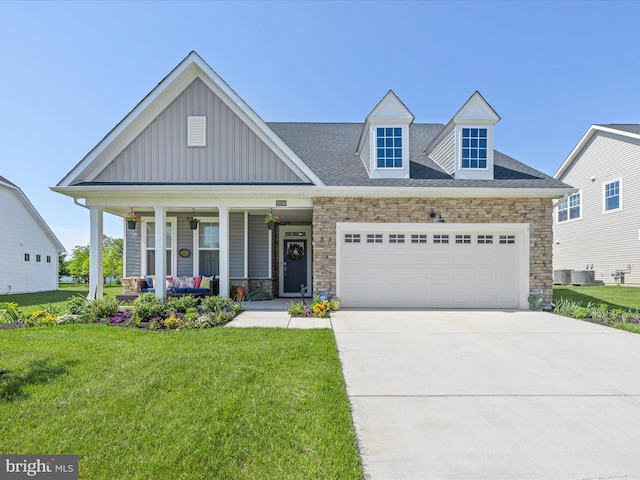 view of front of home featuring covered porch, board and batten siding, stone siding, and a front yard