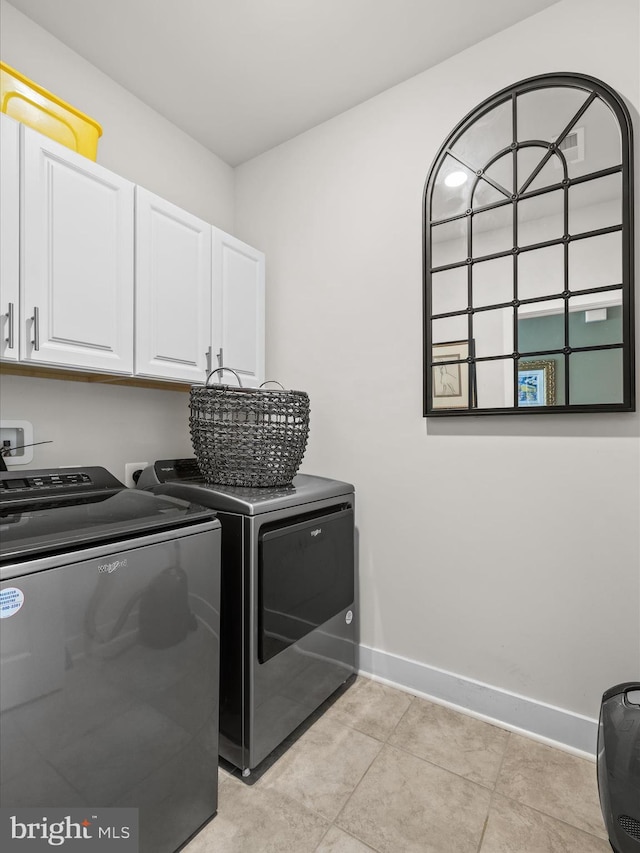 washroom featuring cabinet space, washing machine and dryer, baseboards, and light tile patterned floors