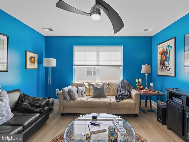 living area featuring wood finished floors, baseboards, and a ceiling fan