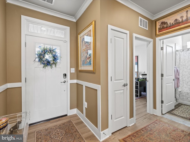 entryway with ornamental molding, light wood-type flooring, and baseboards
