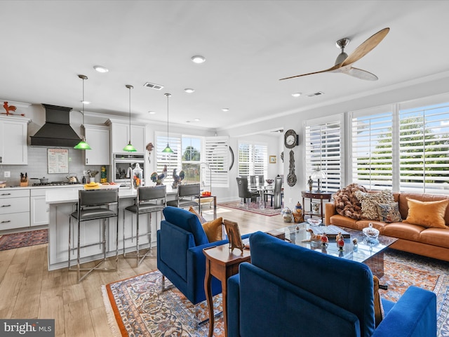 living area featuring a ceiling fan, light wood-style flooring, crown molding, and recessed lighting