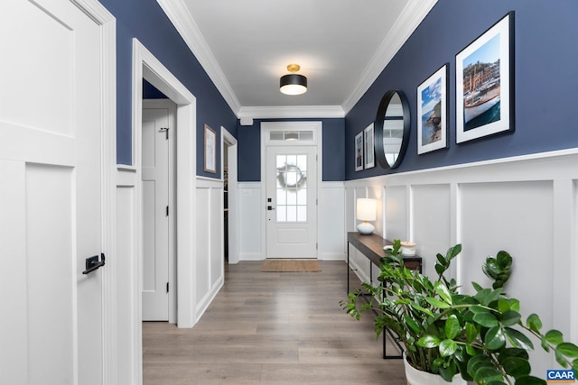 foyer entrance with a decorative wall, crown molding, a wainscoted wall, and wood finished floors