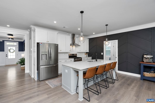 kitchen with stainless steel appliances, a decorative wall, wall chimney exhaust hood, crown molding, and a sink