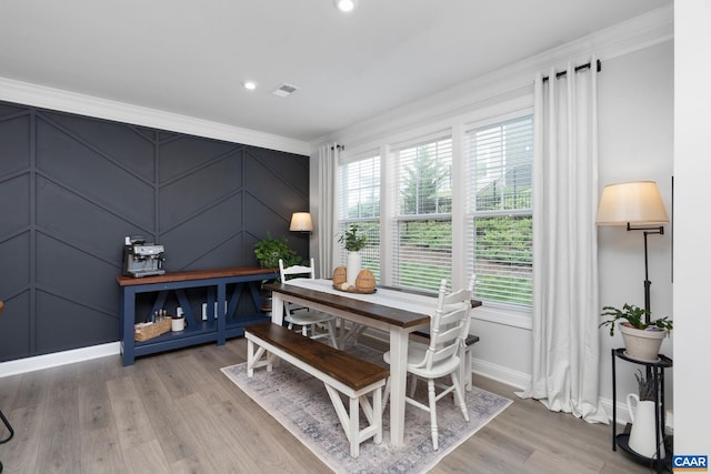 dining space with ornamental molding, baseboards, light wood-style floors, a decorative wall, and recessed lighting