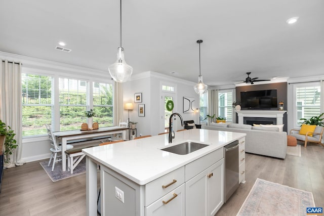 kitchen with a sink, ceiling fan, a fireplace, light countertops, and ornamental molding