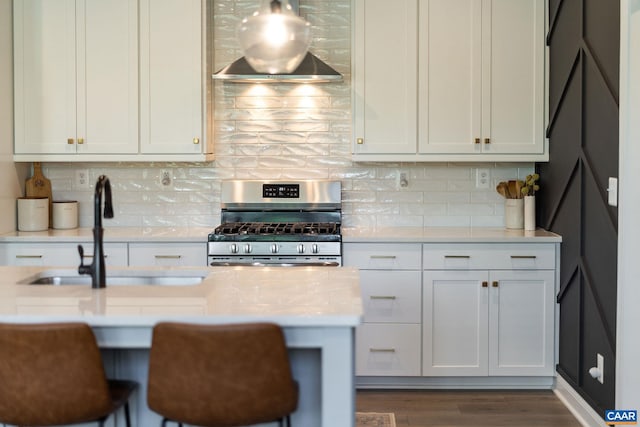 kitchen with stainless steel gas range, a sink, light countertops, and tasteful backsplash