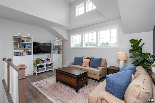 living room with wood finished floors, a towering ceiling, and baseboards