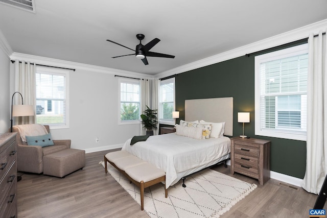 bedroom with crown molding, baseboards, light wood-type flooring, multiple windows, and a ceiling fan