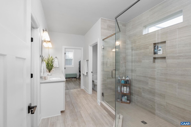 full bath with toilet, a stall shower, vanity, and wood finished floors