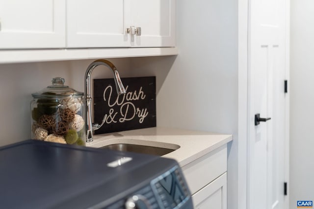 kitchen view of white cabinets, light stone countertops, and a sink