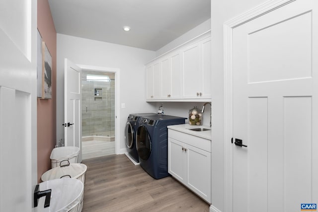 washroom with cabinet space, washing machine and dryer, light wood-style flooring, recessed lighting, and baseboards