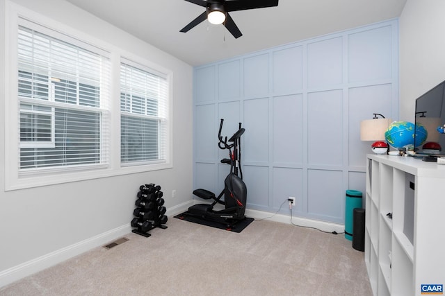workout area with a decorative wall, light colored carpet, a ceiling fan, and baseboards