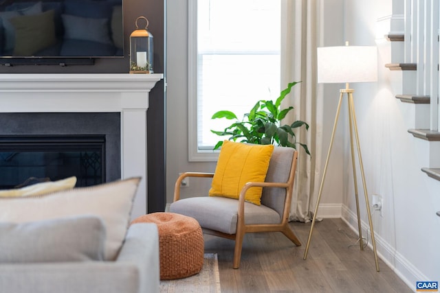 sitting room featuring wood finished floors, baseboards, and a glass covered fireplace