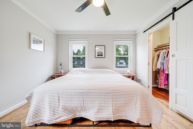 2015 Rollins Dr, Alexandria, VA 22307 - bedroom featuring ornamental molding, a walk in closet, a barn door, light wood finished floors, and a closet