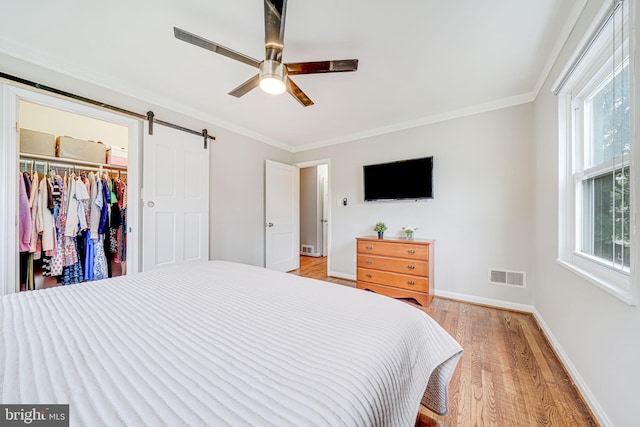 2015 Rollins Dr, Alexandria, VA 22307 - bedroom featuring light wood-type flooring, a barn door, baseboards, ornamental molding, and a walk in closet