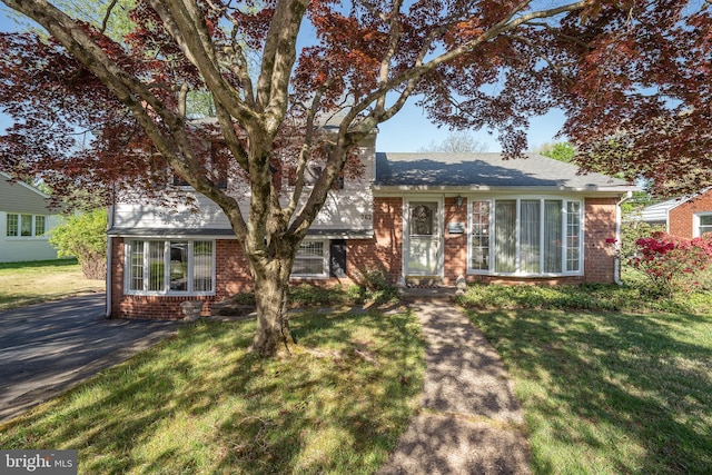 tri-level home featuring brick siding and a front yard