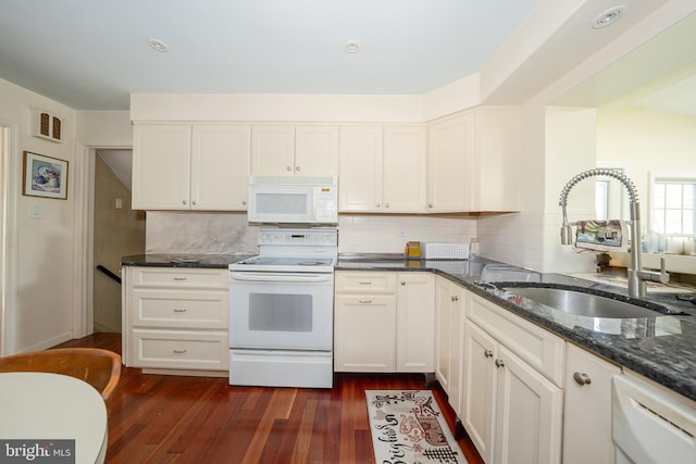 kitchen with white appliances, a sink, dark wood-style flooring, dark stone countertops, and backsplash