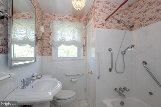 full bathroom with wallpapered walls, toilet, shower / washtub combination, wainscoting, and tile walls