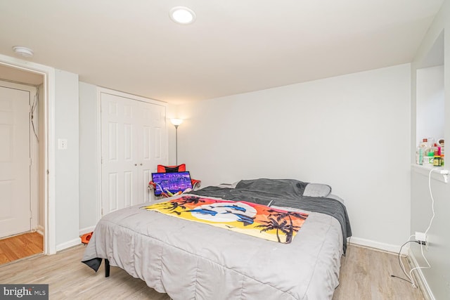 bedroom featuring light wood-type flooring, baseboards, and a closet