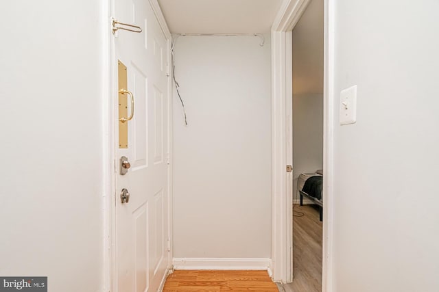hall featuring light wood-type flooring and baseboards