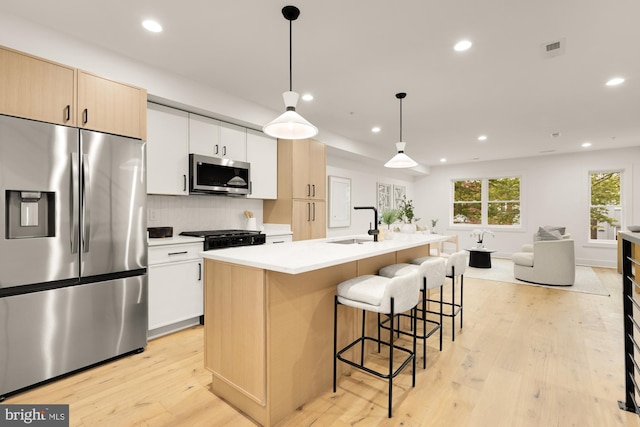 kitchen featuring stainless steel appliances, recessed lighting, light wood-type flooring, open floor plan, and a breakfast bar