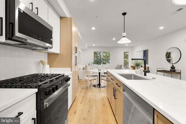 kitchen with stainless steel appliances, a sink, recessed lighting, light wood-type flooring, and backsplash