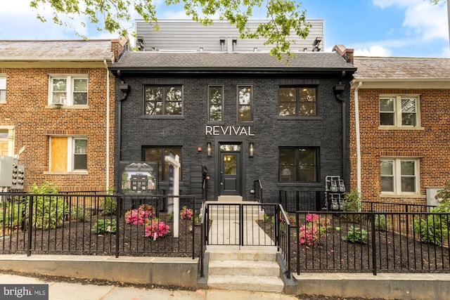 townhome / multi-family property featuring brick siding, fence, and roof with shingles