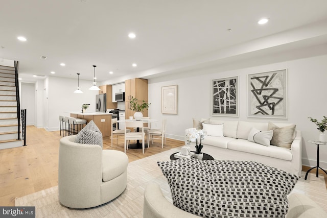 living area with stairway, recessed lighting, baseboards, and light wood-type flooring
